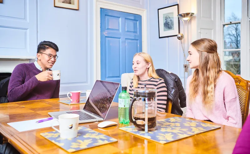 Students having a hot drink and chatting round a table