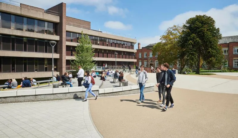 Students walking past Bill Bryson Library while other students sit outside