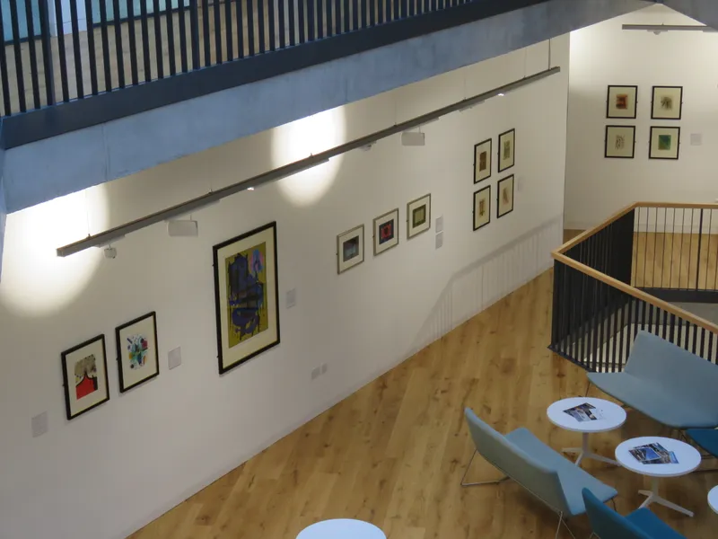 Ten artworks are displayed on a white wall, photographed from above.