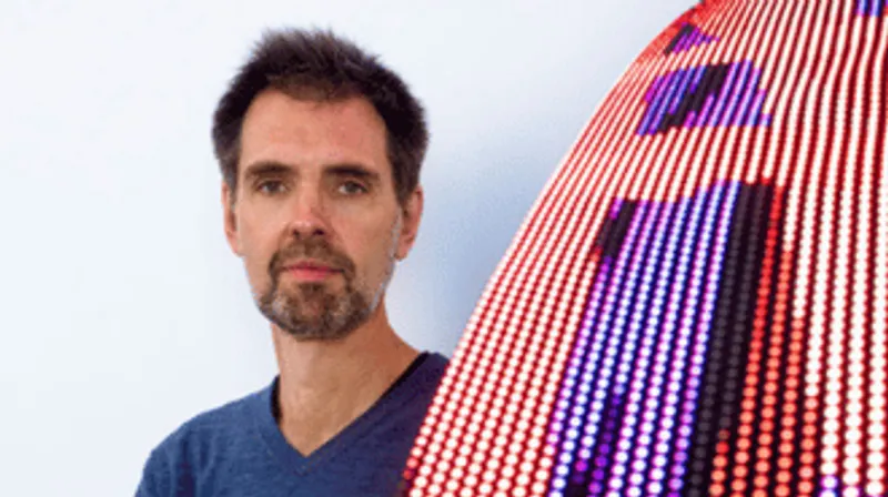 Daniel Canogar next to a piece of illuminated art