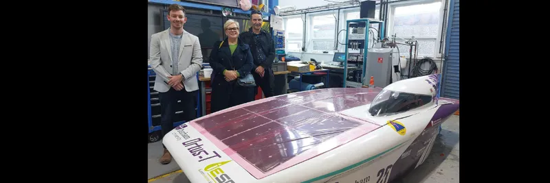 A group of three people in front of our solar car