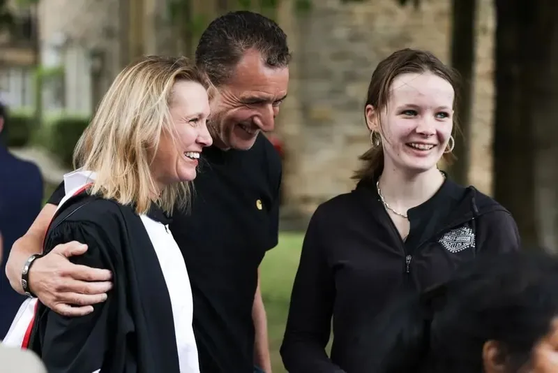 A student in a gown with two guests outside Durham Cathedral