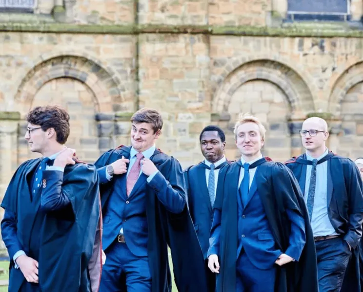 A group of students in gowns outside Durham Cathedral
