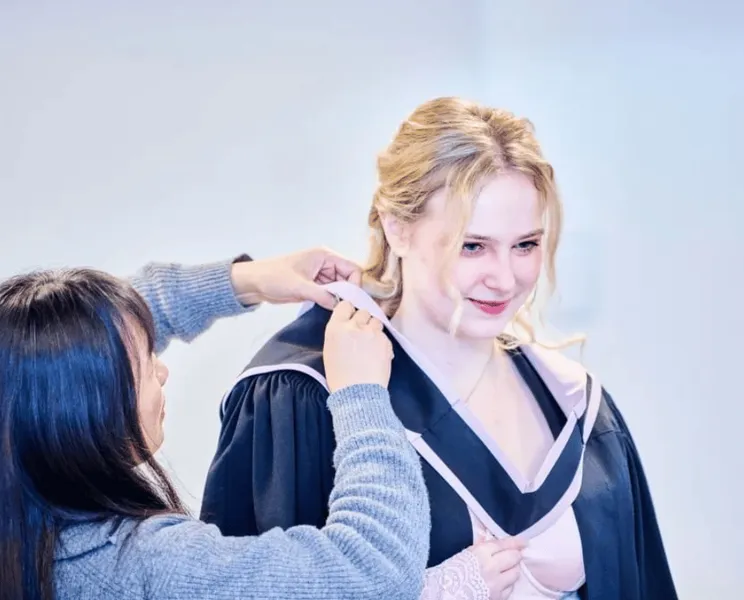 A student having the academic gown pinned into place