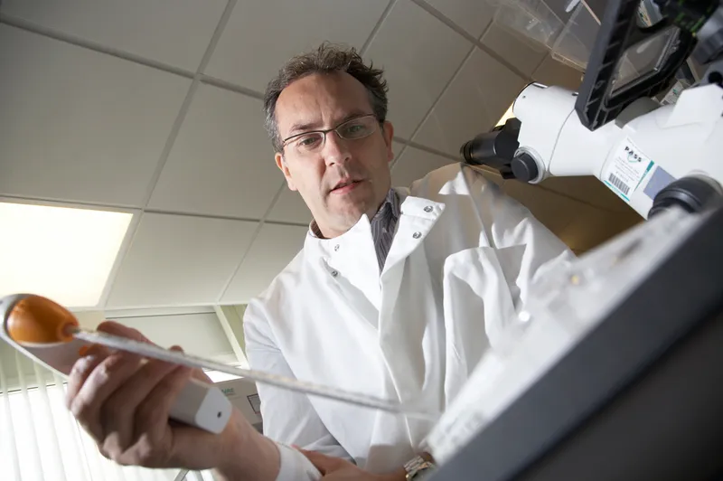 Scientist in lab coat using a pipette