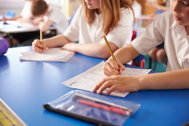 Primary school pupils in class practicing writing.