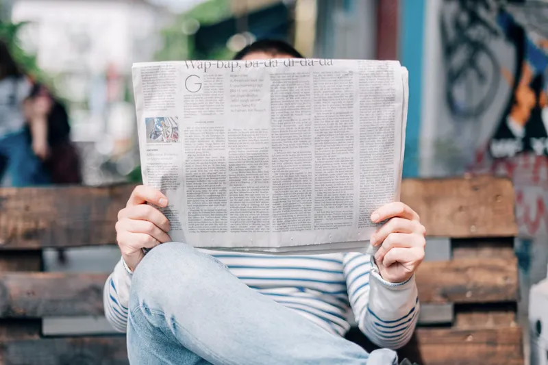 A person on a bench reading a newspaper
