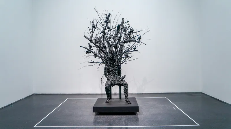 A model of a metal tree emerging from a sitting person, with various birds and animals sitting on the branches.
