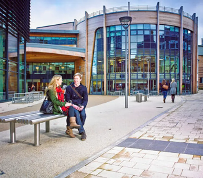 Two students sitting on a bench in front of the Palatine Centre.