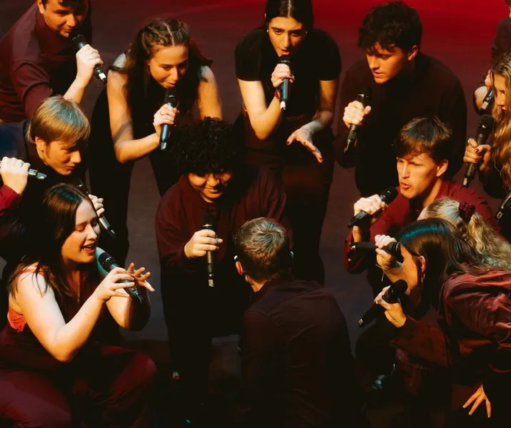 A Capella choir members sing and dance all dressed in red.
