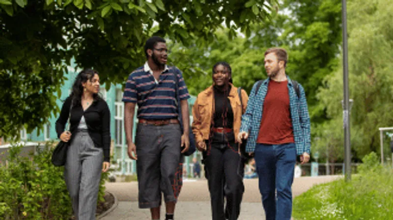 Four students walking and chatting through the campus