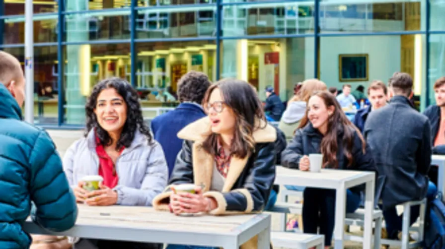 A large group of students sat chatting on benches