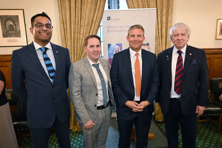 Four men in suits standing in front of a pull-up banner