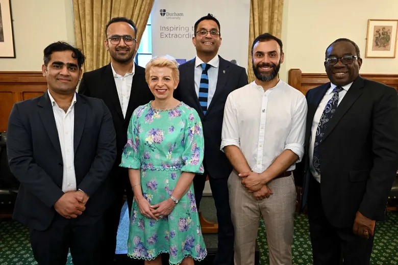 Four men and a woman standing in front of a pull-up banner
