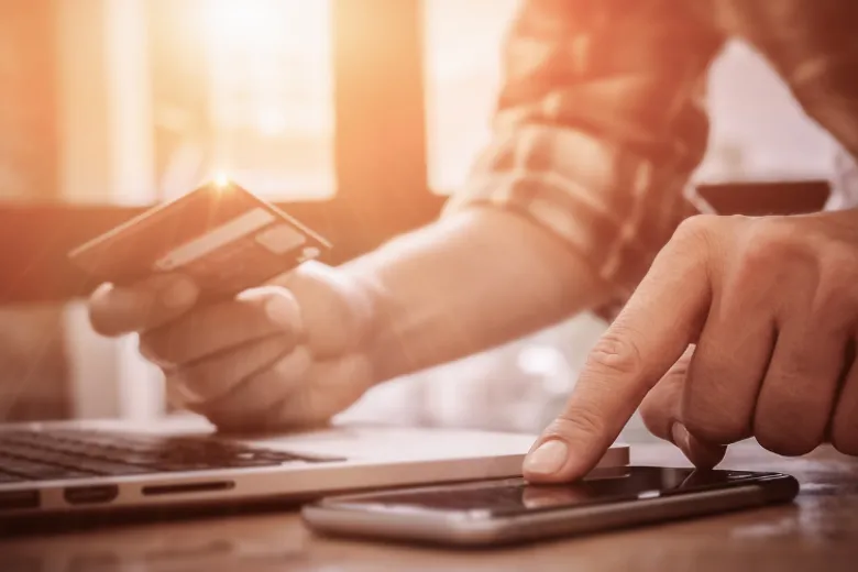 Man hands with a credit card, calculator and laptop.