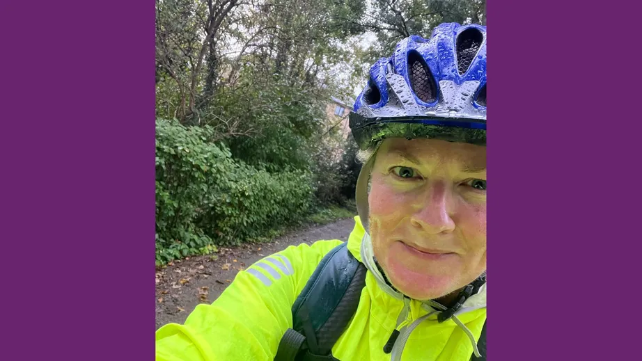 A close-up of a women in a fluorescent yellow jacket and royal blue bike helmet in the rain