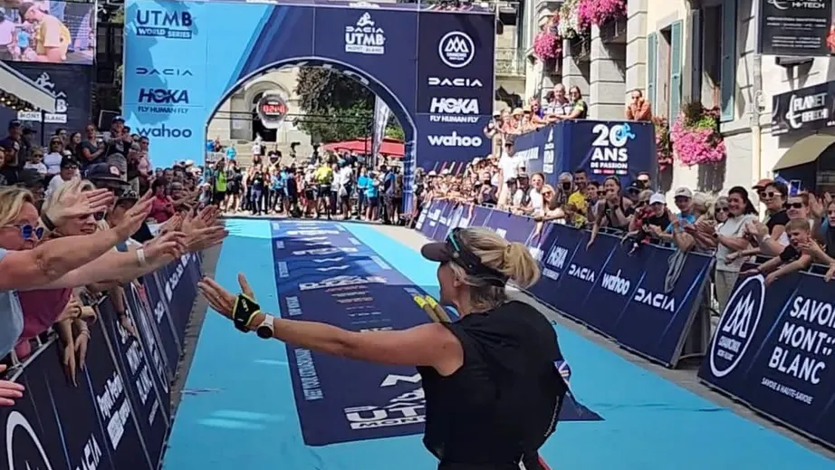 A women running away from the camera towards the finishing arch of the Ultra Trail de Mont Blanc ultramarathon