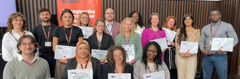 A group of people sitting and standing and looking at the camera. They are smiling and holding certificates.