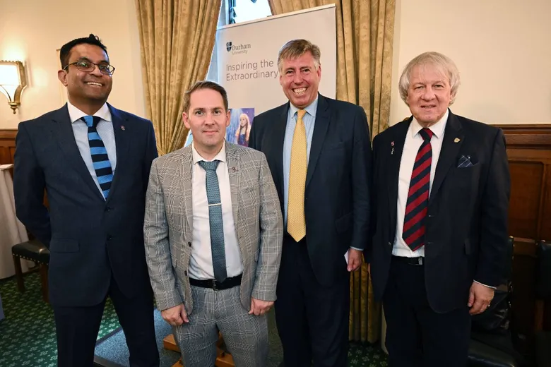 Four men in suits standing in front of a pull-up banner