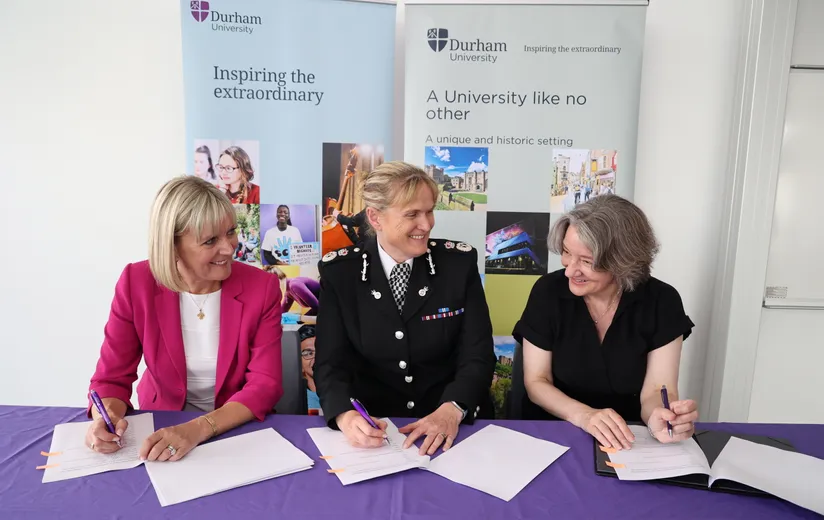 Three women chatting while seated at a table, signing a document