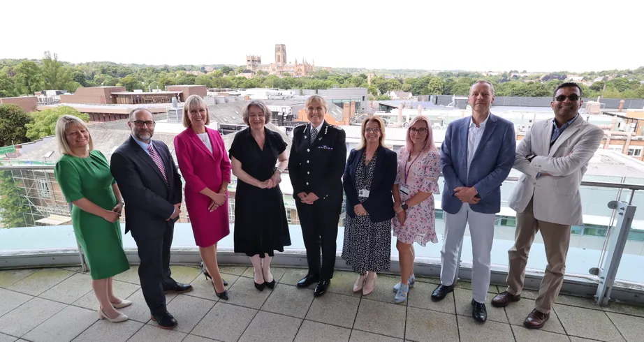 Men and women stood on a balcony, with Durham Cathedral in the distance behind them