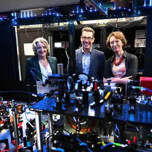 A man and two women smile at the camera, with scientific equipment in the foreground