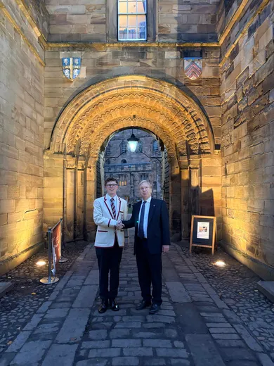 Two men standing in front of a stone castle gatehouse