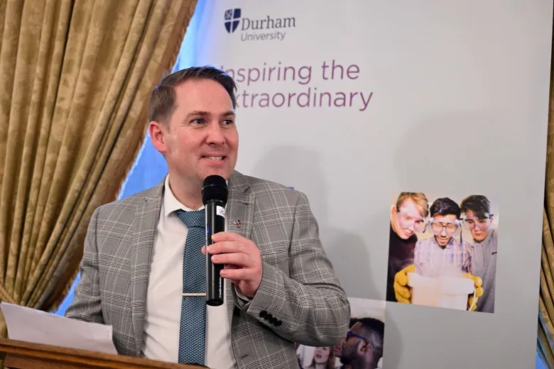 Man in suit and tie speaking into handheld microphone
