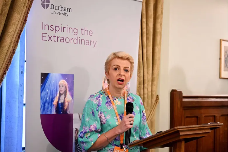 Woman speaking into handheld microphone, standing at lectern