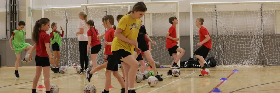 Children playing football in a sports hall