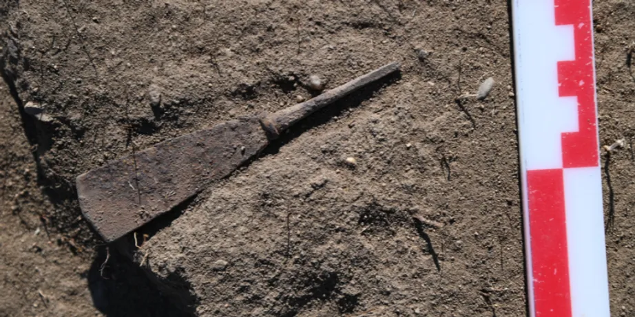 An item shaped like a large knife or trowel lays on the ground