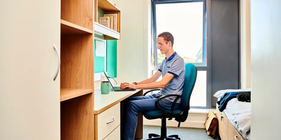 an image of a boy sitting in a bedroom at a desk