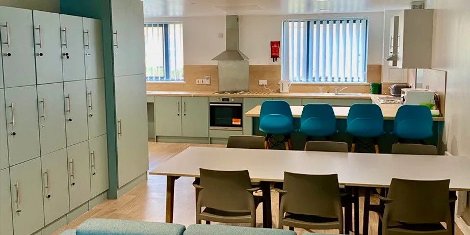 A picture of the inside of a town house kitchen. Shown are a table with chairs, bar seating at a work space, and a large prep and cooking area.