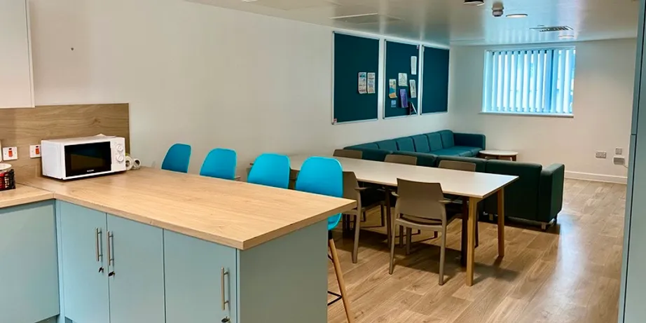 A picture of the inside of a town house kitchen. Shown is the kitchen bar, dining area with a table and chairs, and a sitting area with sofas.