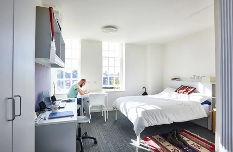Student studying in Sheraton Park Studio with desk, storage and double bed